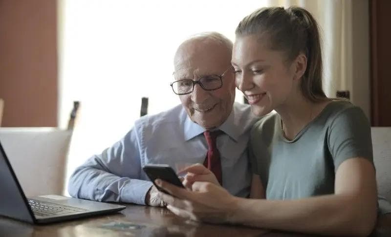 Senior receiving in-person technology support while using a smartphone at home