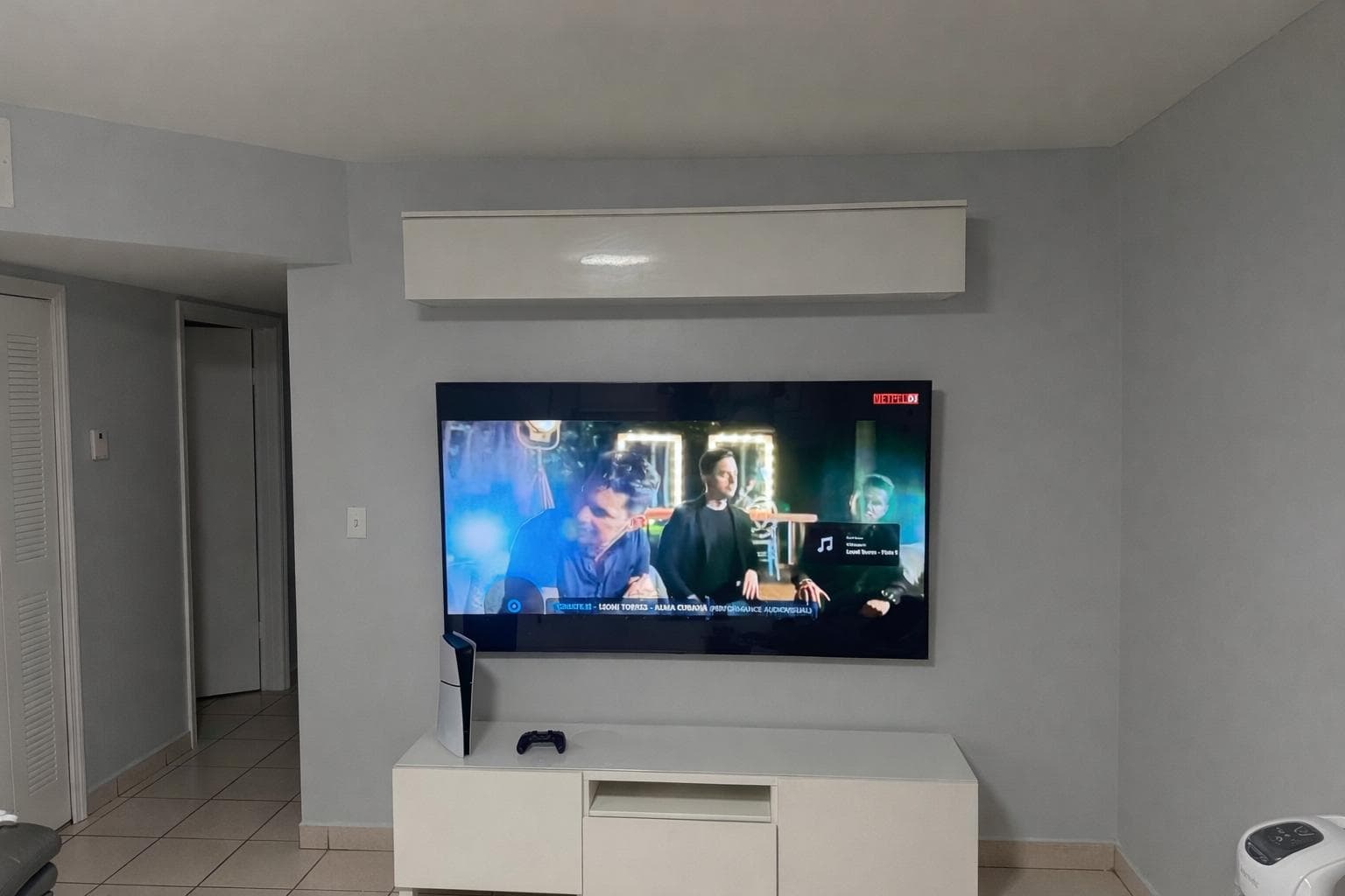 75-inch TV professionally wall mounted above white media console in modern Miami living room with hidden cables by CallTechCare