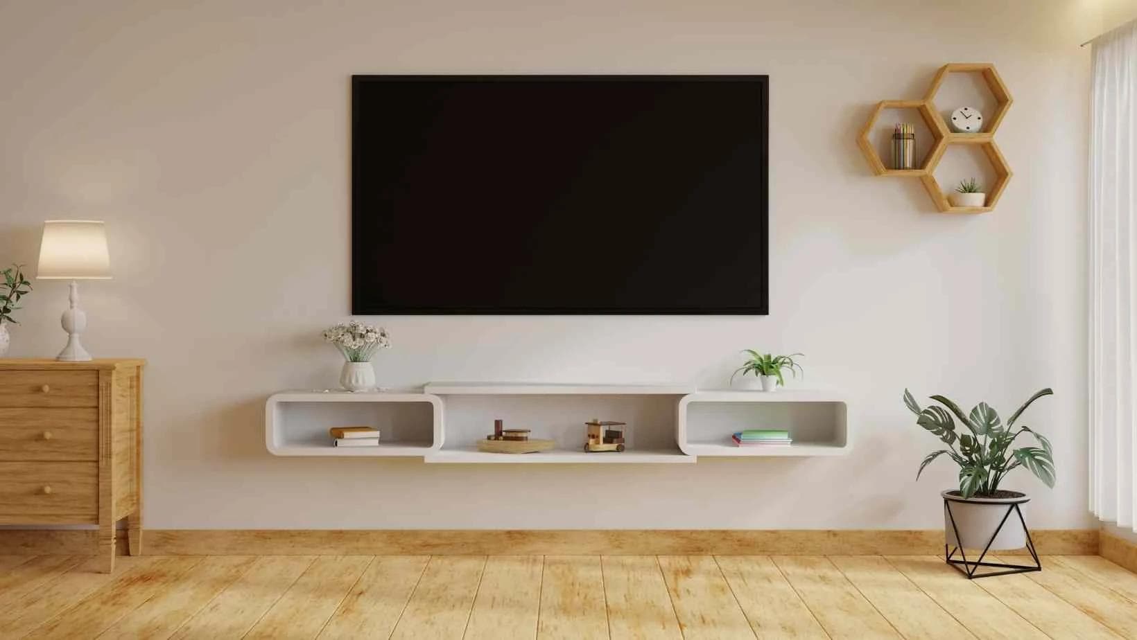 Wall-mounted flat-screen TV in a modern living room with floating shelves and decorative plants